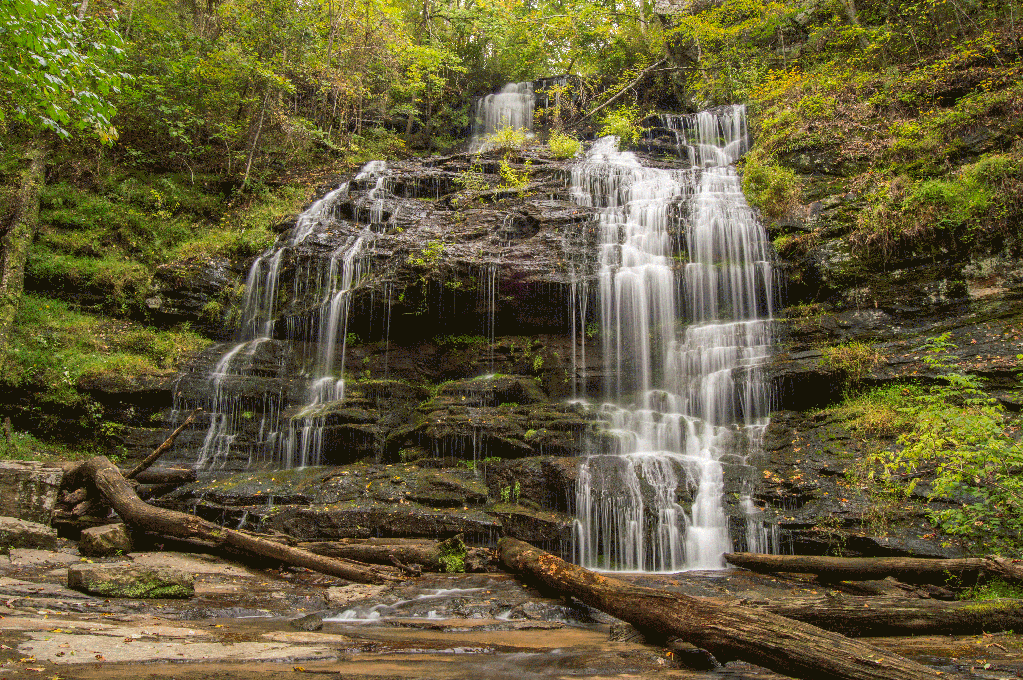 Station Cove Falls descending a staircase of rocks surrounded by lush green woodland